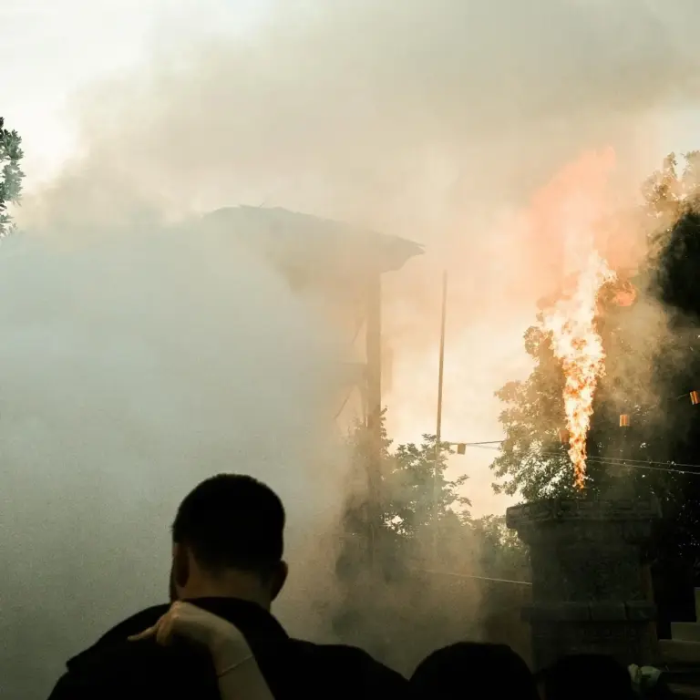 Festivalbesucher beobachten eine spektakuläre Feuershow mit hohen Flammen und dichten Rauchschwaden an der DachüberKopf Festival-Bühne